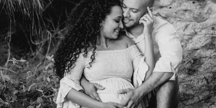 eine werdende-mutter-mit-werdenden-vater freuen sich auf ihr kind und sitzen am ufer eines flusses