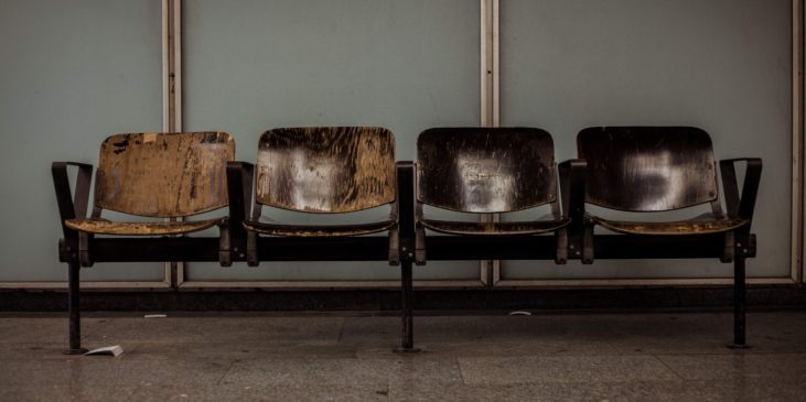 Vier abgesitzene, alte Holzstühle in einem Wartezimmer eine Frauenarzt Praxis zu sehen beim warten auf die Untersuchung einer schwangeren Frau