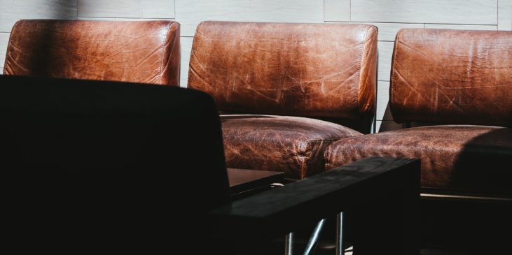 Titelbild ist eine Reihe von fünf braunen Retro Ledersitzen, die ein Wartezimmer darstellen sollen