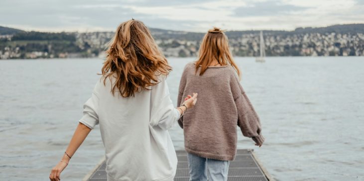 Zwei Frauen laufen gemeinsam über einen Steg im See