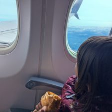 Mädchen schaut aus Fenster im Flugzeug