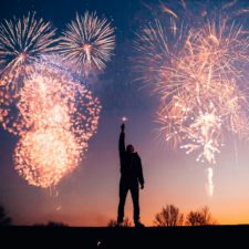 Ein Mann vor dem Nachthimmel zu Neujahr mit Feuerwerk im Himmel