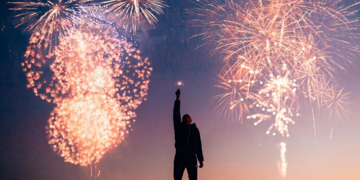 Ein Mann vor dem Nachthimmel zu Neujahr mit Feuerwerk im Himmel