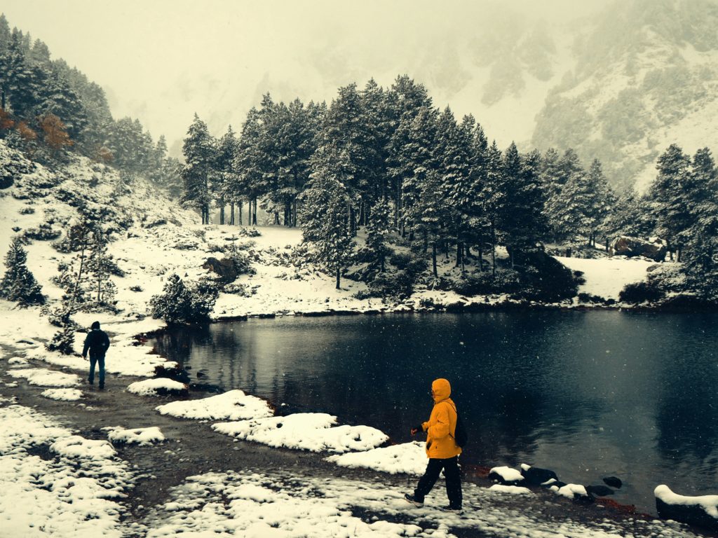 Zwei Menschen beim Winterwandern zwischen Bäumen und Bergen