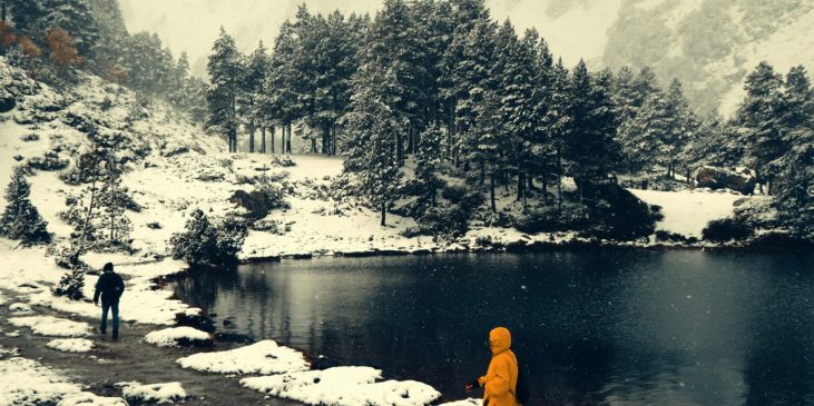 Zwei Menschen beim Winterwandern zwischen Bäumen und Bergen