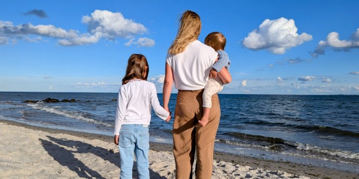 Mutter mit Kindern blickt aufs Meer