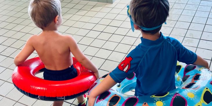 zwei Kleinkinder mit Schwimmreifen im Hallenbad