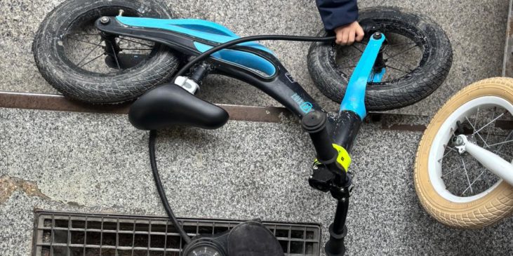 Kind mit Laufrad und Mama pumpt Luft rein