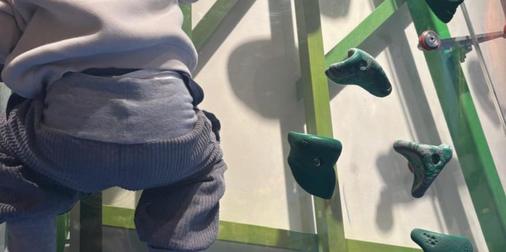 Kind klettert eine Boulderwand hoch