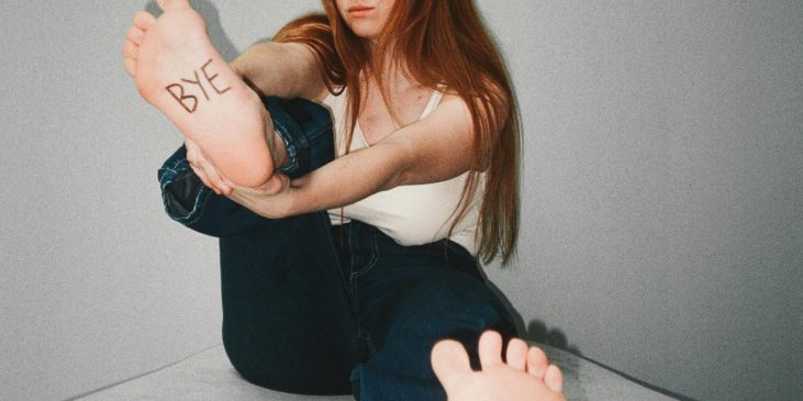 Frau mit Aufschrift "Bye" und "Hi" auf den Fußsohlen