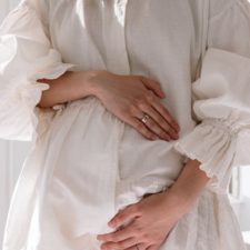 Vorbereitungen auf die Hausgeburt Frau in weißem Kleid hält ihren Bauch