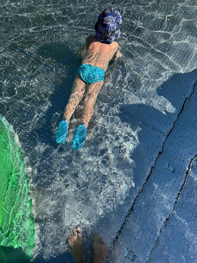 Kind mit Sonnenhut schwimmt im Wasser