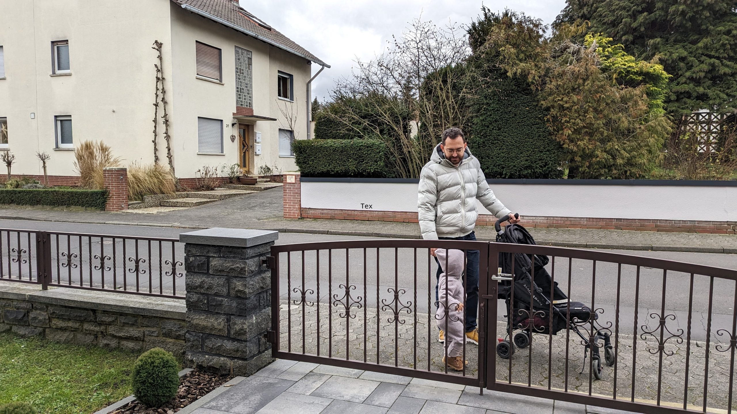 Vater mit Kind und Kinderwagen vor dem Hof-Tor