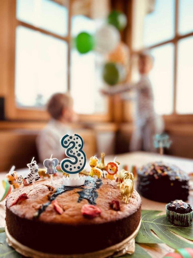 gedeckter Geburtstagstisch mit Kuchen, auf dem eine Kerze in Form der Zahl drei steckt