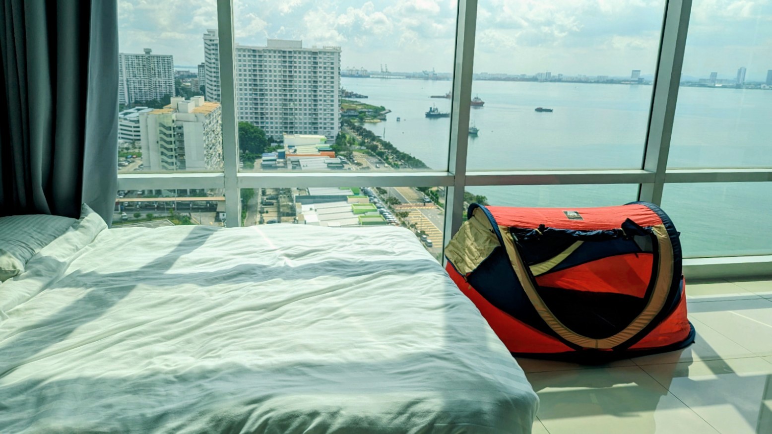 Faltbares Babyzelt als Reisebett im Hotelzimmer mit Blick auf die Stadt