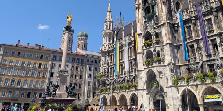 Blick über den belebten Marienplatz in München mit Mariensäule, Frauenkirche und dem Neuen Rathaus.